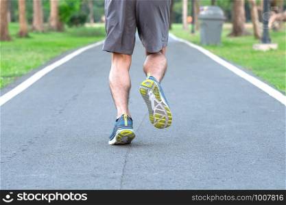 Young athlete man with running shoes in the park outdoor, male runner jogging on the road outside, asian Fitness walking and exercise on footpath in morning. wellness and sport concepts