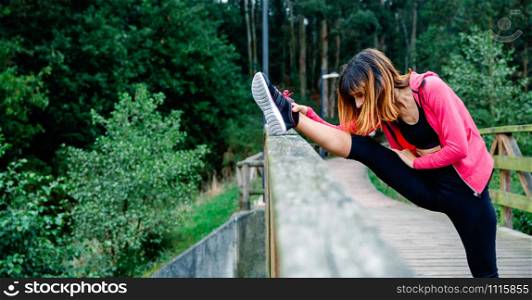 Young athlete woman doing leg stretch outdoors