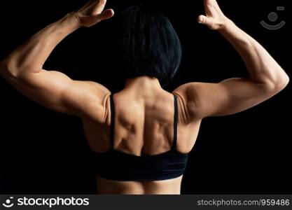 young athletic girl with black hair turned her back and showing a muscular back and arms, low key