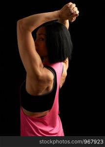 young athletic girl with black hair turned her back and showing a muscular back and arms, low key