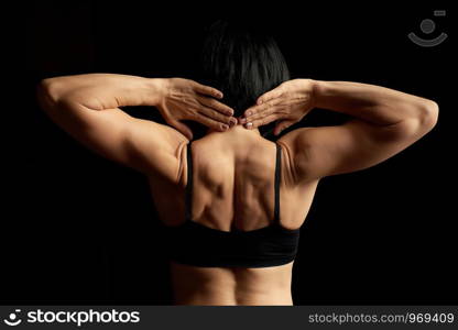 young athletic girl with black hair turned her back and showing a muscular back and arms, low key