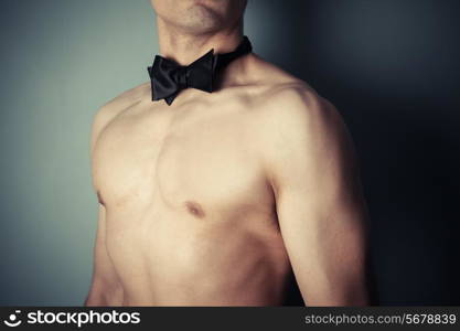 Young athletic man is wearing nothing but a bow tie