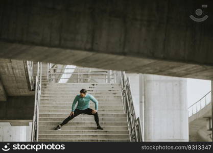 Young athletic man stretching on stairs outdoor after running