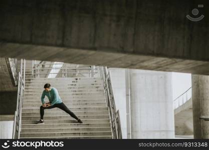 Young athletic man stretching on stairs outdoor after running