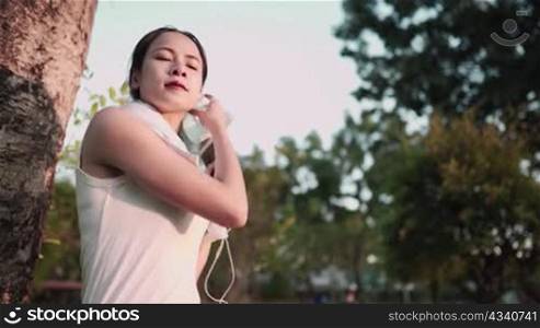 Young athletic pretty asian woman removing her face mask getting ready for jogging and putting on earphones in park, running outdoors during quarantine concept, self-isolation, social distancing