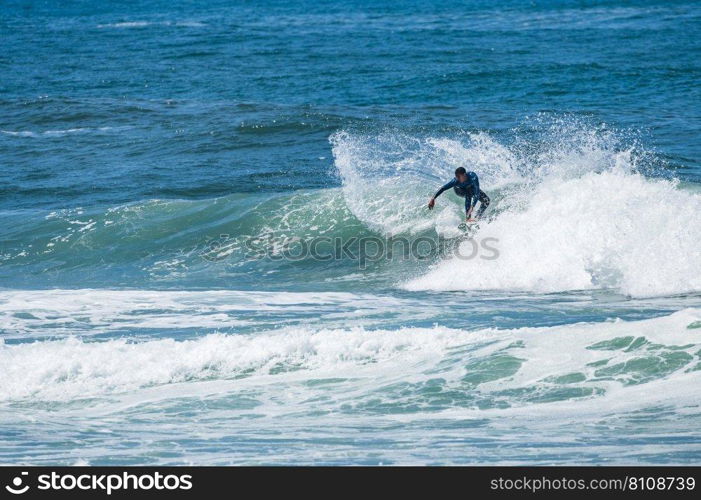 Young athletic surfer rides the wave in Furadouro Beach in Ovar, Portugal.