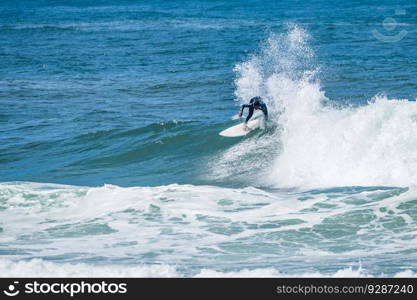 Young athletic surfer rides the wave in Furadouro Beach in Ovar, Portugal.