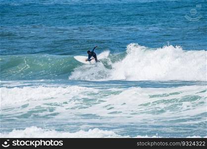 Young athletic surfer rides the wave in Furadouro Beach in Ovar, Portugal.