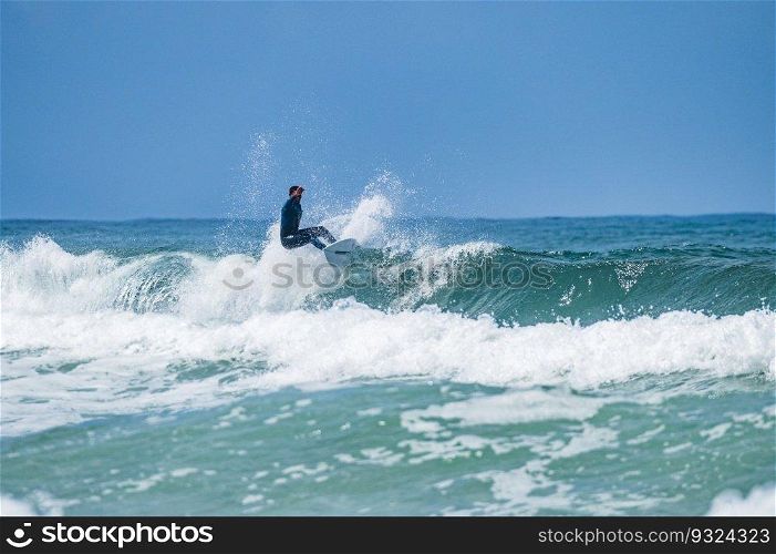 Young athletic surfer rides the wave in Furadouro Beach in Ovar, Portugal.
