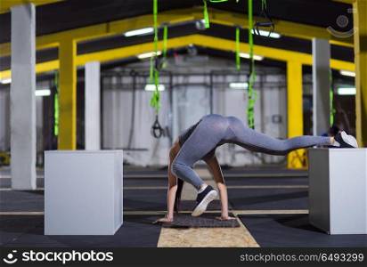 young athletic woman doing gymnastic exercise between two fit boxes at crossfitness gym. woman working out gymnastic exercise on fit boxes