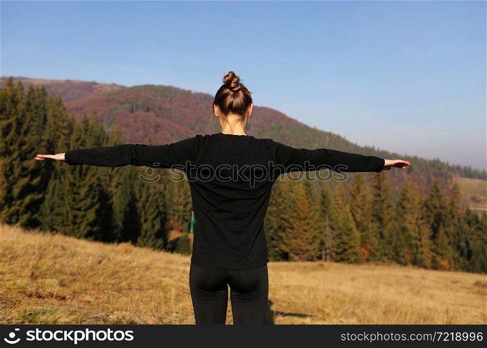 Young athletic woman stretching before intense morning workout at sunset or sunrise in beautiful mountain location. The concept of energy, health and harmony during sports.. Young athletic woman stretching before intense morning workout at sunset or sunrise in beautiful mountain location. The concept of energy, health and harmony during sports