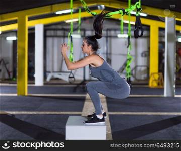 young athletic woman training jumping on fit box at crossfitness gym. woman working out jumping on fit box
