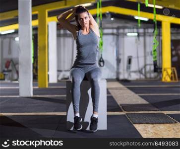 young athletic woman warming up and stretching on fit box at crossfitness gym. woman warming up and stretching on fit box