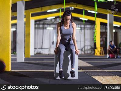 young athletic woman warming up and stretching on fit box at crossfitness gym. woman warming up and stretching on fit box