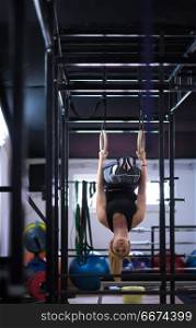 young athletic woman working out on gymnastic rings at the cross fitness gym. woman working out on gymnastic rings