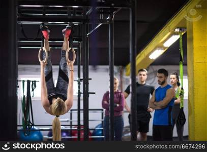 young athletic woman working out with personal trainer on gymnastic rings at the cross fitness gym. woman working out with personal trainer on gymnastic rings