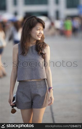 young attractive asian woman walking out door with relaxing and easy feeling