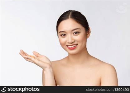 Young attractive asian woman who takes a capsule or pill. Isolated over white background. Young attractive asian woman who takes a capsule or pill. Isolated over white background.