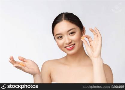 Young attractive asian woman who takes a capsule or pill. Isolated over white background. Young attractive asian woman who takes a capsule or pill. Isolated over white background.