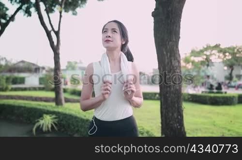 Young attractive asian women is breathing freshly before jogging outdoor or running with a green park background, While sun sets in summer, Concept healthy running and outdoor exercise