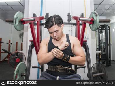 Young attractive athlete sitting on gym equipment