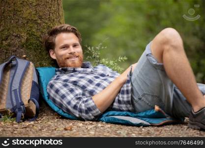 young attractive bearded man sitting under tree and resting