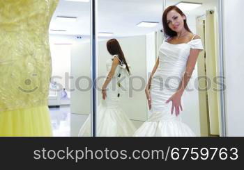 Young attractive bride trying on wedding gown in bridal shop