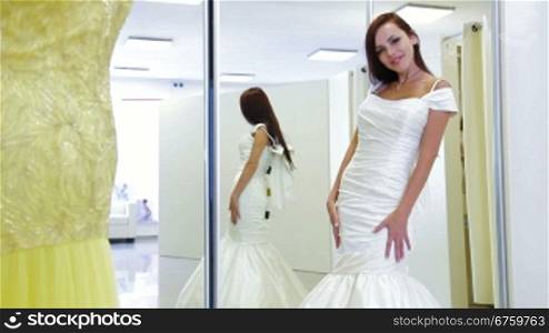 Young attractive bride trying on wedding gown in bridal shop