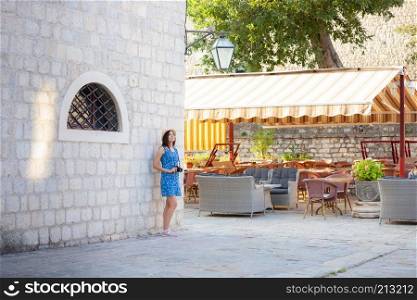 Young attractive cheerful travel girl walking with camera in old Mediterranean city. Summer travel concept