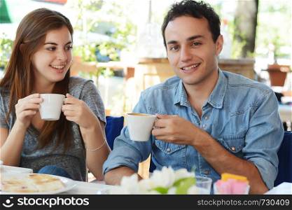 Young attractive couple enjoying a coffee at the coffee shop. Outdoors.