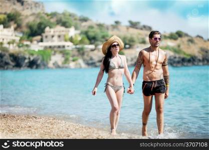 Young attractive couple is walking through the water at the beach