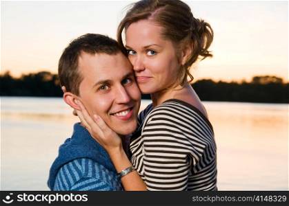 young attractive couple near lake at sunset