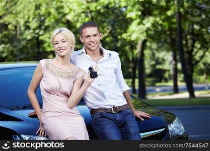 Young attractive couple standing by the car with the keys