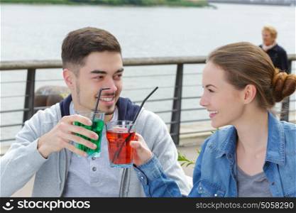 young attractive couple toasting with cordials at bar terrace