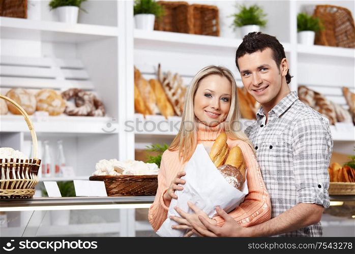Young attractive couple with bread in shop