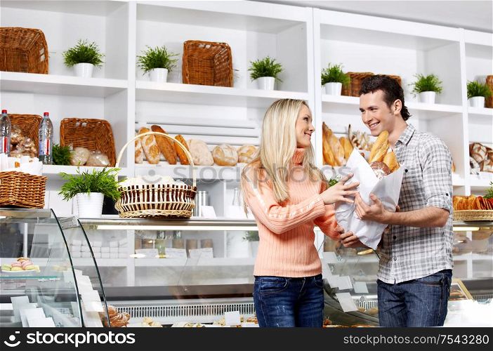 Young attractive couple with bread in shop