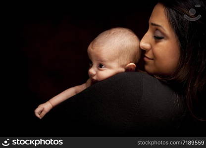 Young Attractive Ethnic Woman Holding Her Newborn Baby Under Dramatic Lighting.