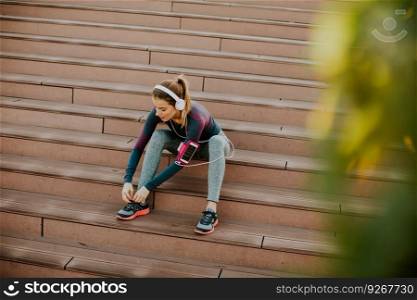 Young attractive female runner taking break after jogging outdoors