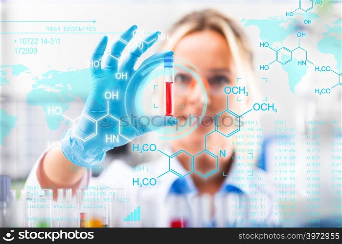 Young attractive female scientist in protective eyeglasses and gloves examining test tube with red liquid sample substance probe in the scientific chemical research laboratory with futuristic scientific air interface with chemical formulas and research data in the foreground