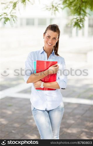 Young attractive female student with notebooks in her hands