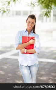 Young attractive female student with notebooks in her hands