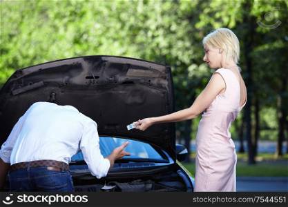 Young attractive girl gives money to a man who repairs cars