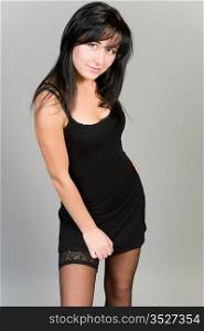 young attractive girl in a black dress on a gray background