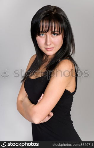 young attractive girl in a black dress on a gray background