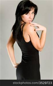 young attractive girl in a black dress on a gray background