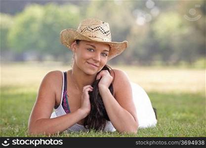 young attractive girl lying on grass wearing a summer hat
