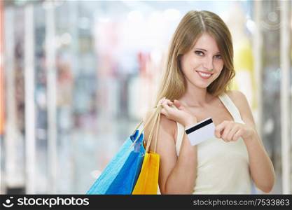 Young attractive girl with shopping and credit card in store