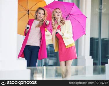 Young attractive girlfriends with the colorful umbrellas