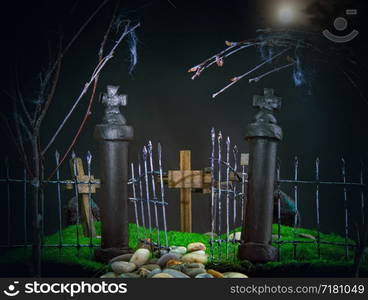 young attractive green-eyed red-haired witch in a classic pointed hat on a background of a gloomy cemetery. dark toy cemetery