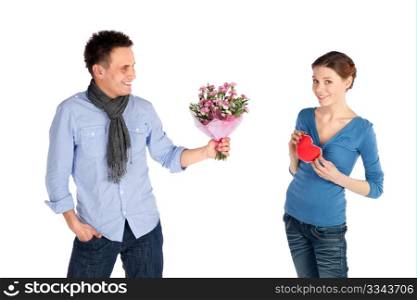Young attractive happy couple in love. Woman giving her heart, man offering flowers, isolated on white background.
